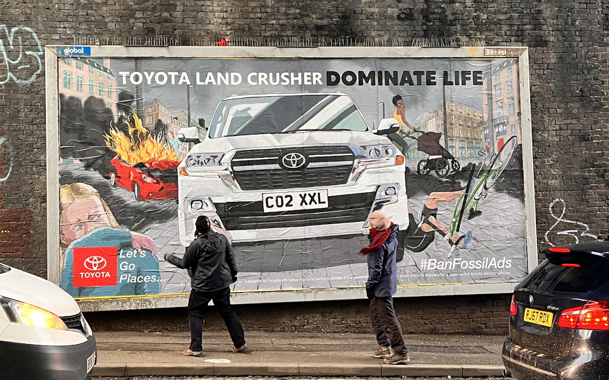 A billboard shows an SUV driving towards the viewer. On either side of the SUV people can be seen fleeing. A caption at the top of the billboard reads "Toyota Land Crusher. Dominate Life"