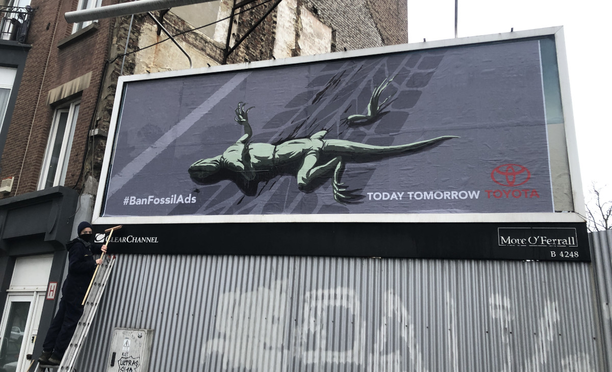 A billboard shows a lizard lying dead on a road. Below it is a Toyota logo and the words "Today Tomorrow Toyota"