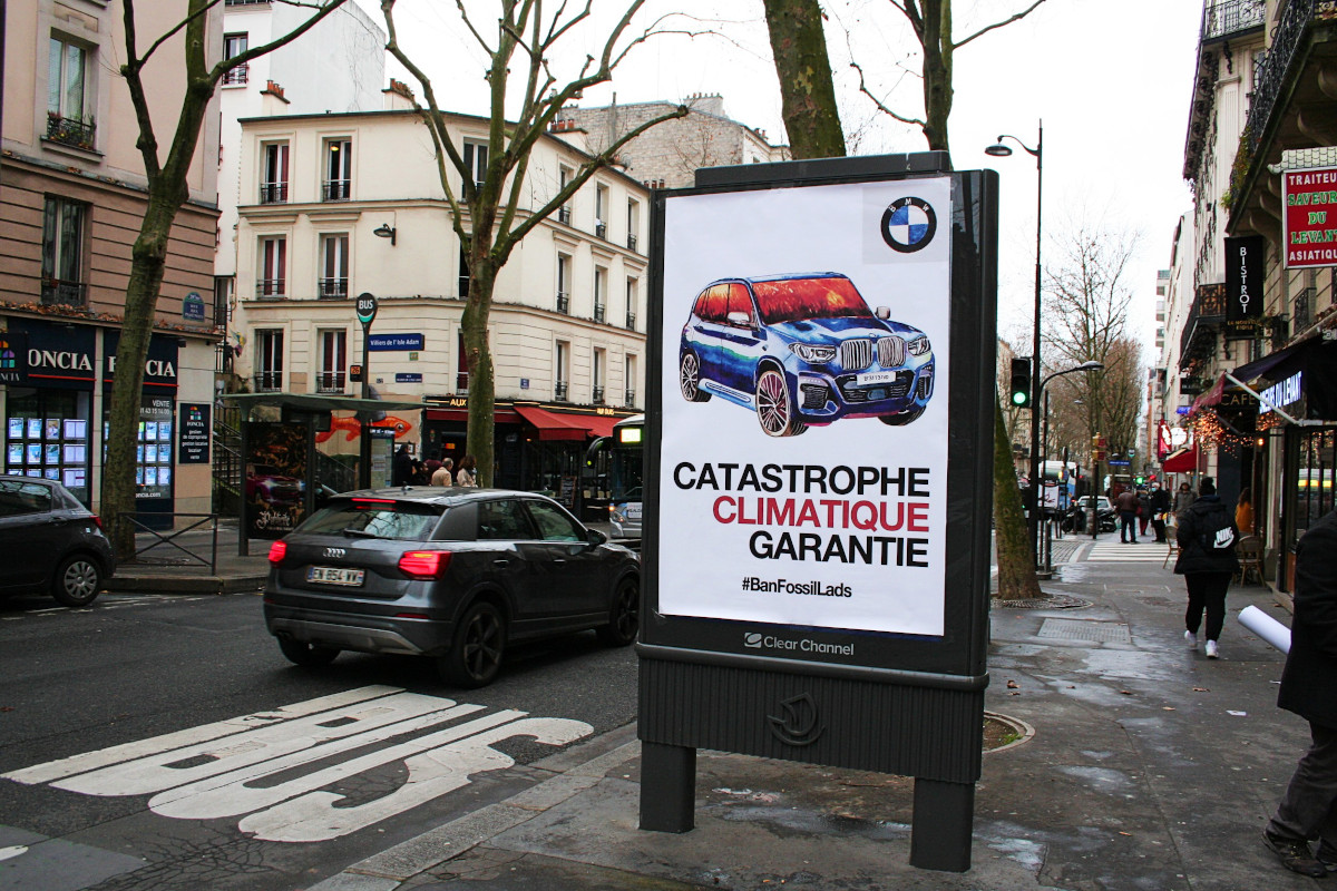 A poster shows a large BMW car with flames reflected in the windows. Below is the text "Catastrophe Climaatique Garantie"