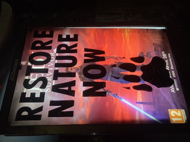 A bus stop poster over written with the words "restore nature now"