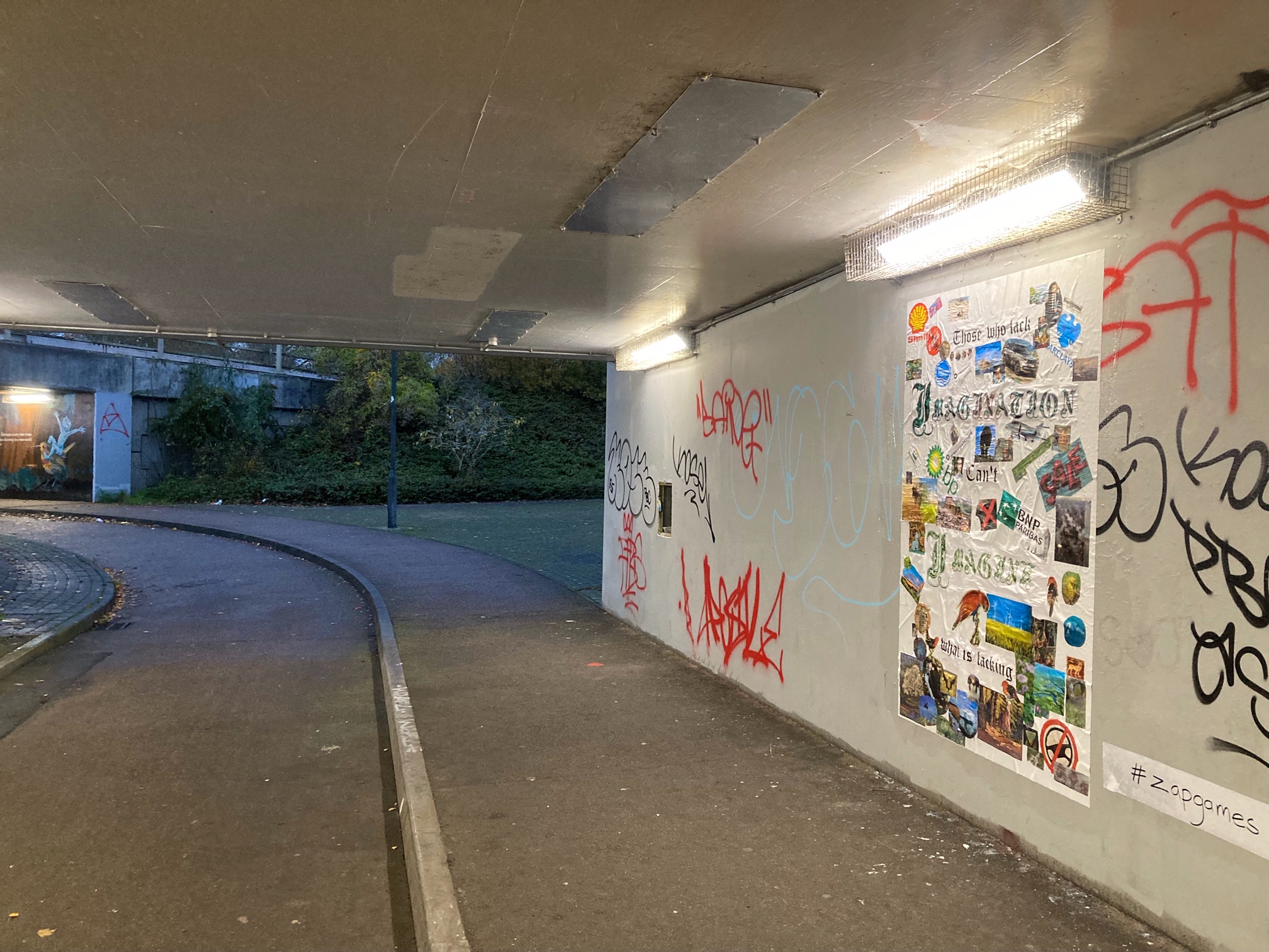 An underpass wall has a large poster stuck to it showing a melange of images about nature and fossil fuels